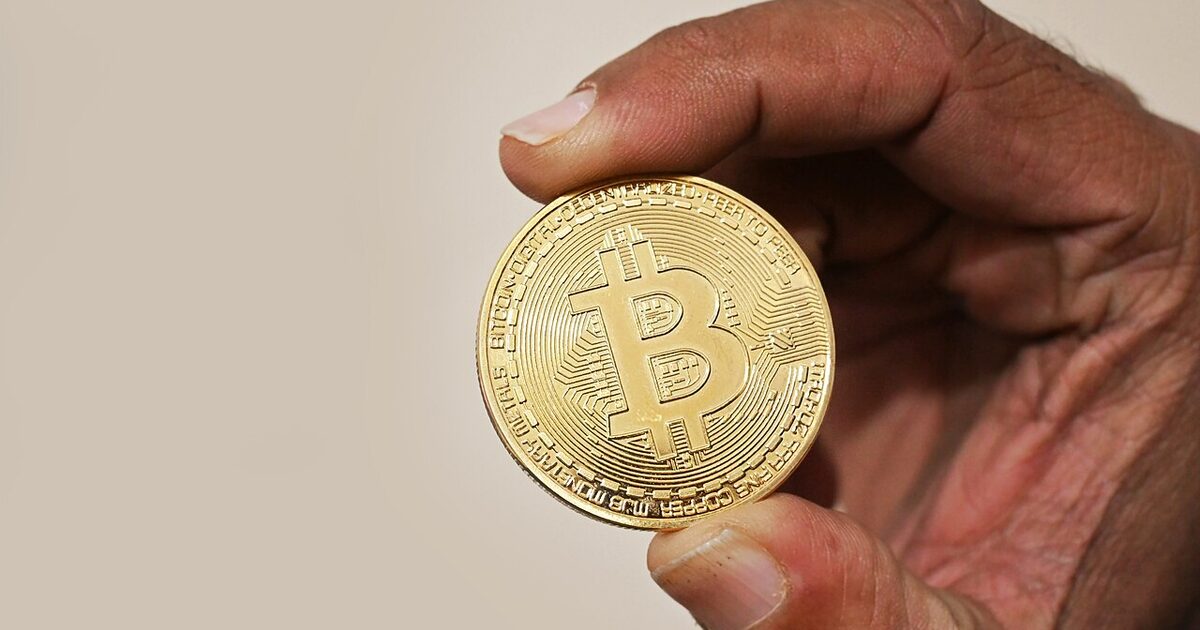 A hand holding a physical cryptocurrency coin